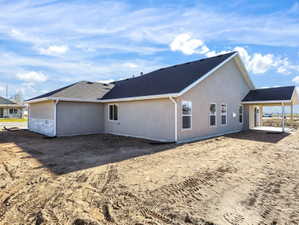 Contemporary exterior featuring stucco siding with a stone accent foundation, a covered patio, and white-framed windows