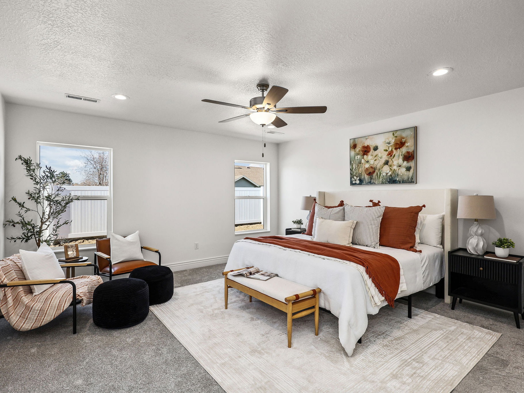 Spacious bedroom featuring light gray carpeting, recessed lighting, a ceiling fan, and multiple windows