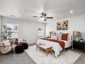 Spacious bedroom featuring light gray carpeting, recessed lighting, a ceiling fan, and multiple windows