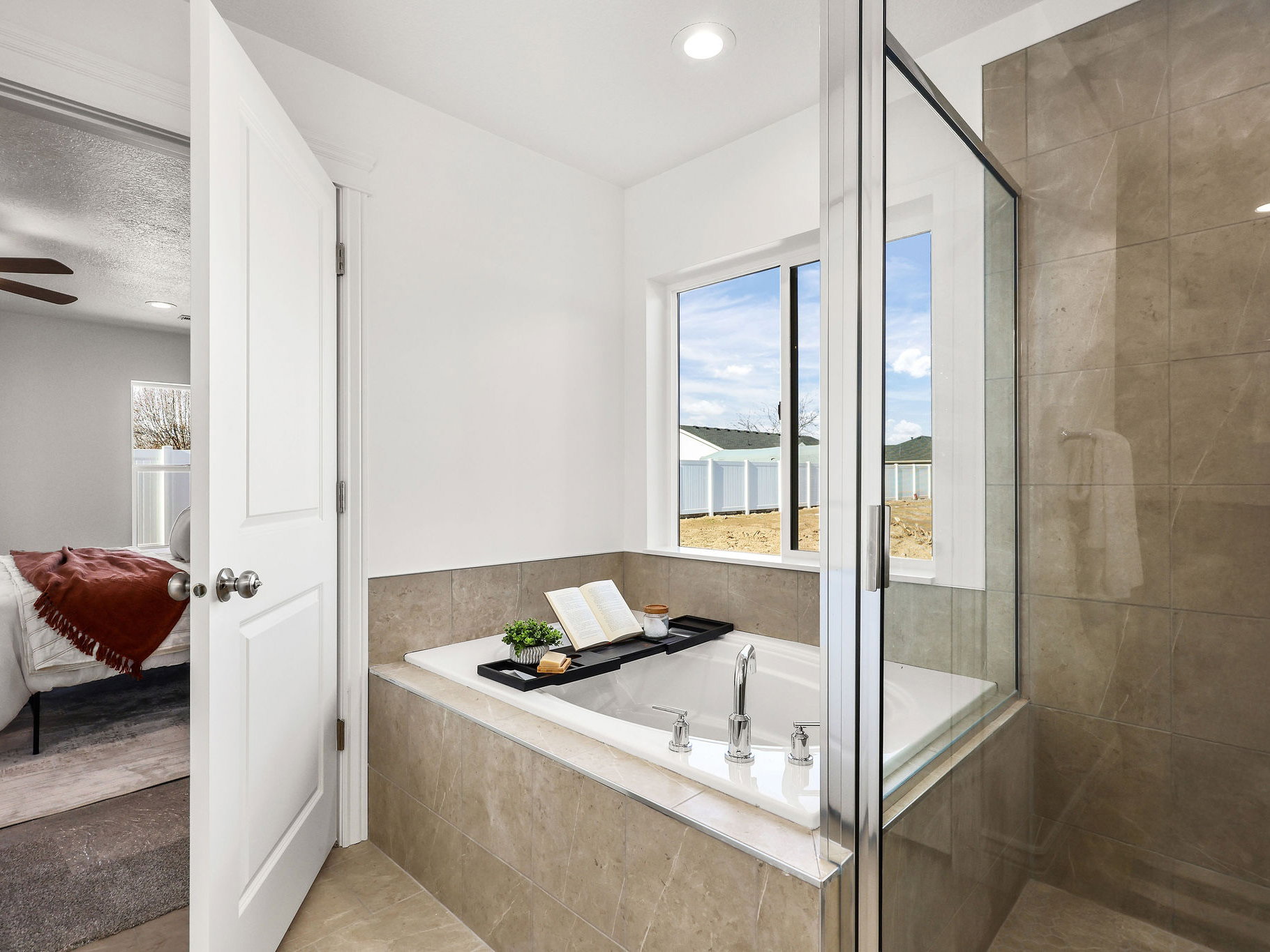 Bathroom featuring a built-in soaking tub with chrome fixtures, a clear glass shower enclosure, and large format wall tiling