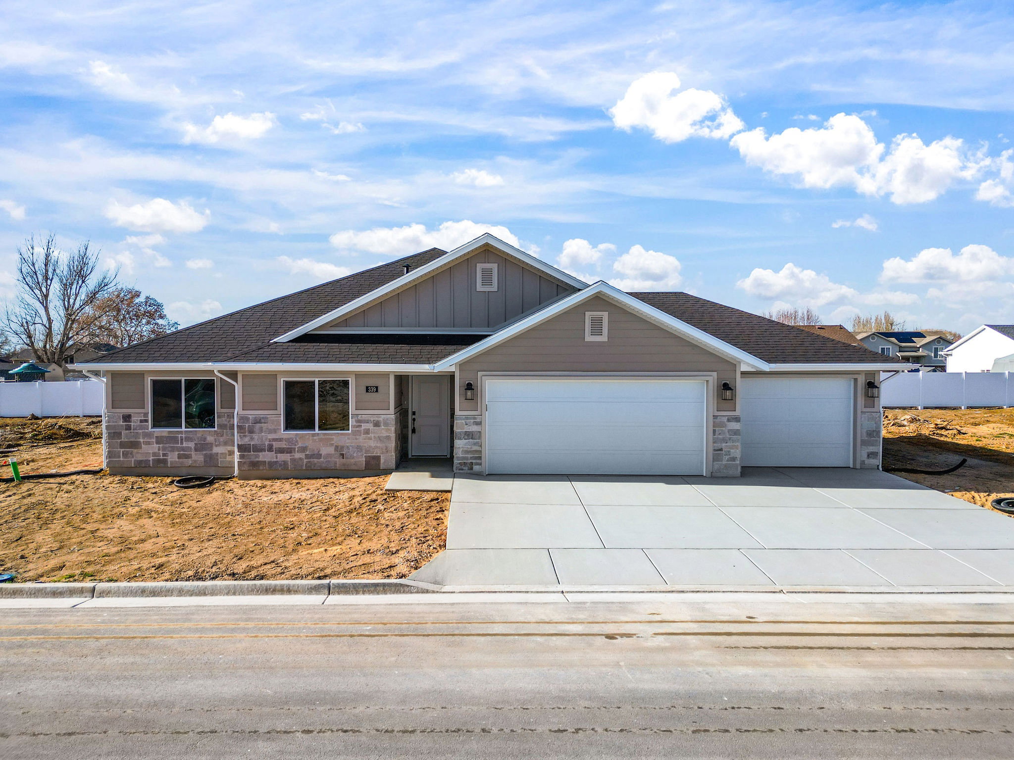 Contemporary single-story residence featuring a two-tone exterior with light stone veneer accents and tan siding
