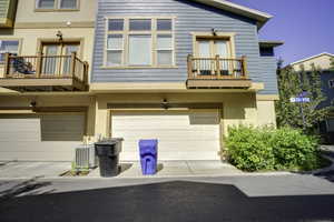Townhome exterior featuring a two-car garage, upper-level balcony with wood railing, and blue horizontal siding