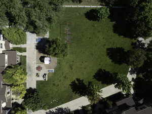 Manicured green space featuring a large lawn area, mature trees, concrete pathways, and recreational equipment