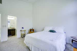 Carpeted sleeping area featuring a vaulted ceiling and direct access to a private bath