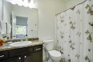 Bathroom featuring a dark wood-finish vanity with ample storage, a speckled countertop, and a white oval sink with a chrome faucet