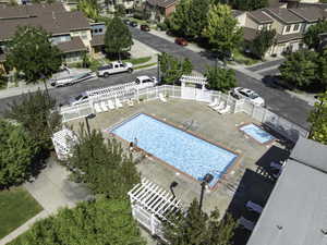 Community swimming pool and spa with surrounding white picket fencing, concrete decking, and lounge seating