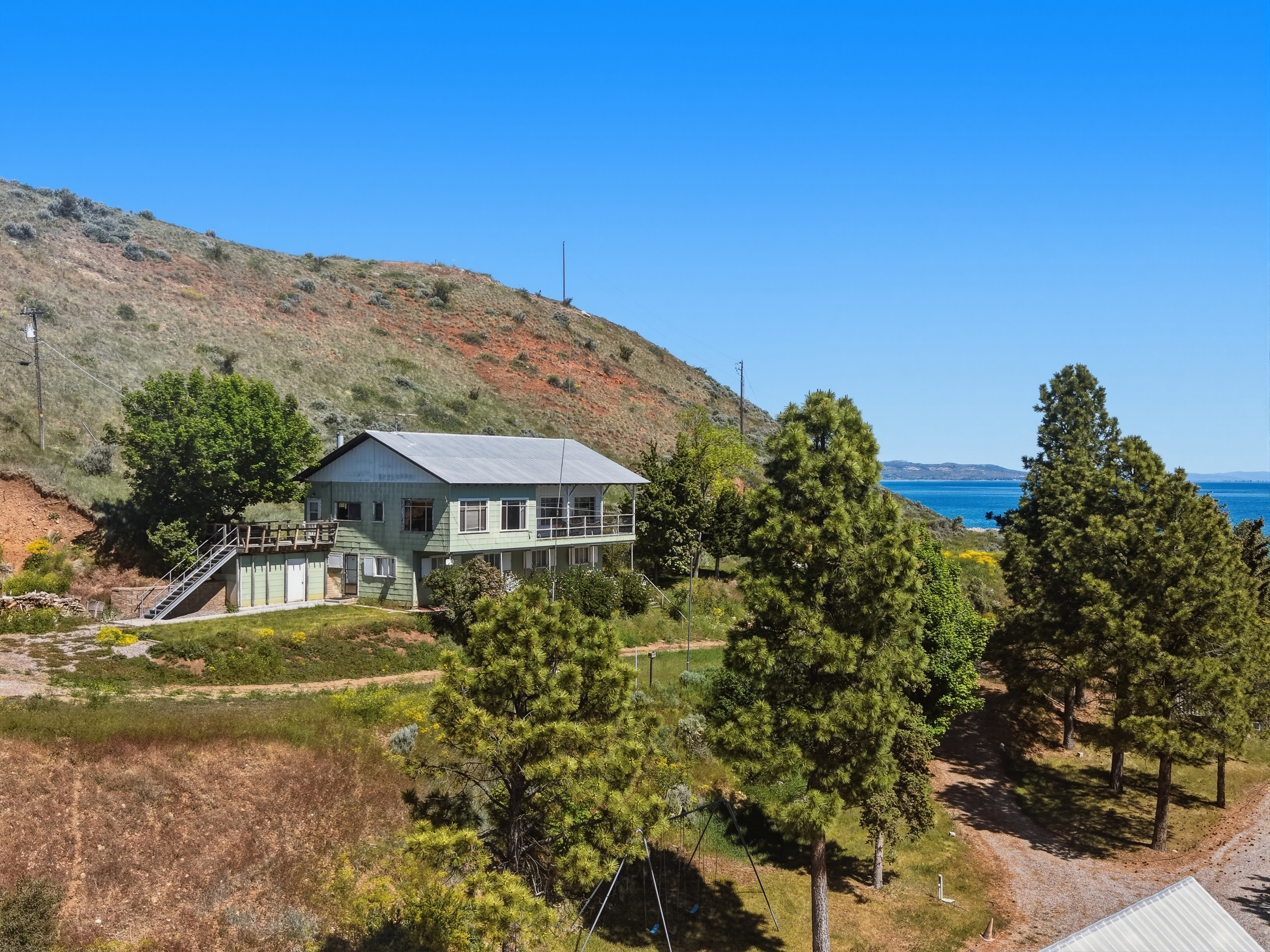 Two-story structure with a metal roof and a multi-level deck, set against a hillside