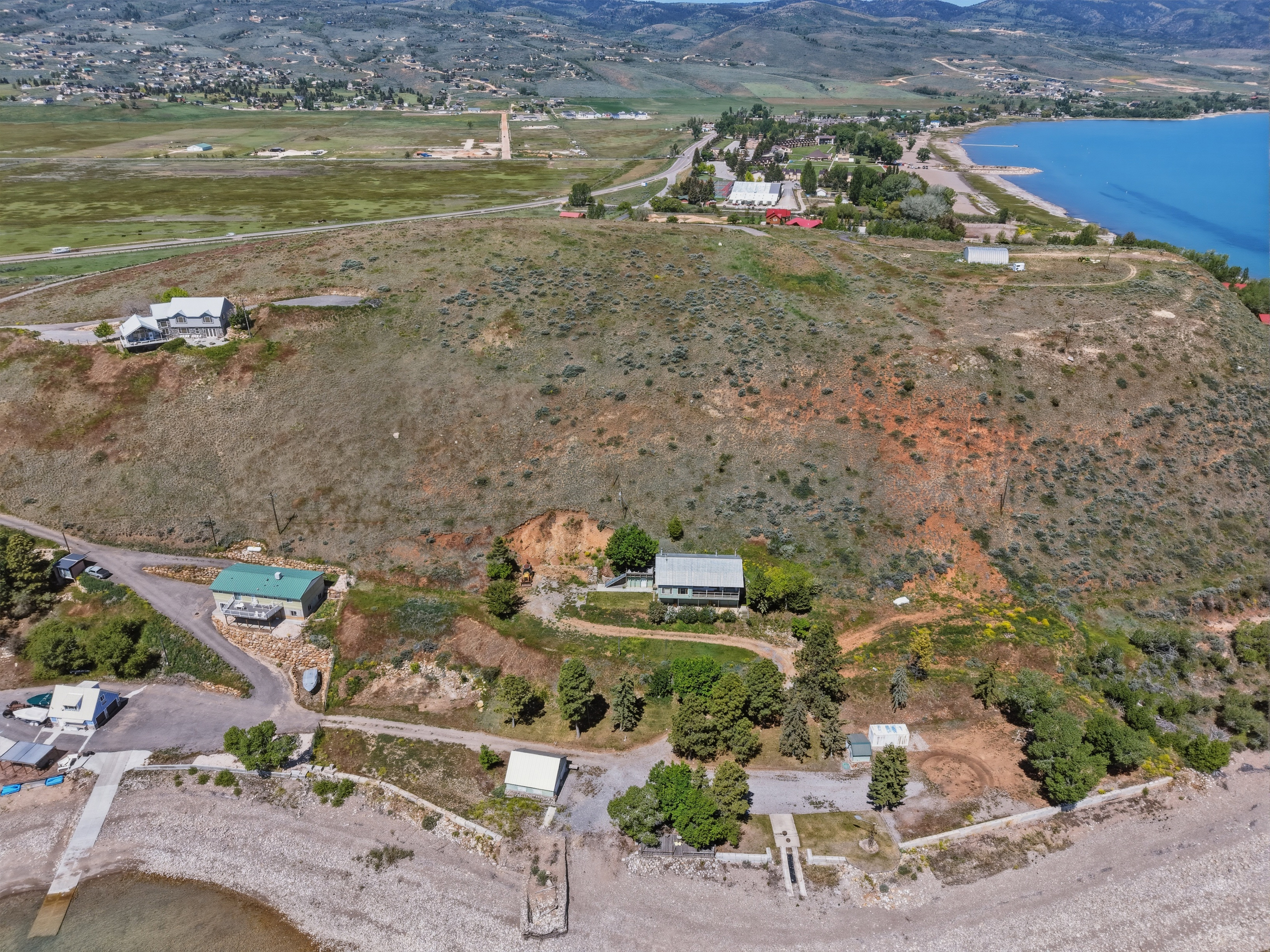 Aerial perspective featuring a waterfront property with direct access to the water, a private dock, and a multi-level residence