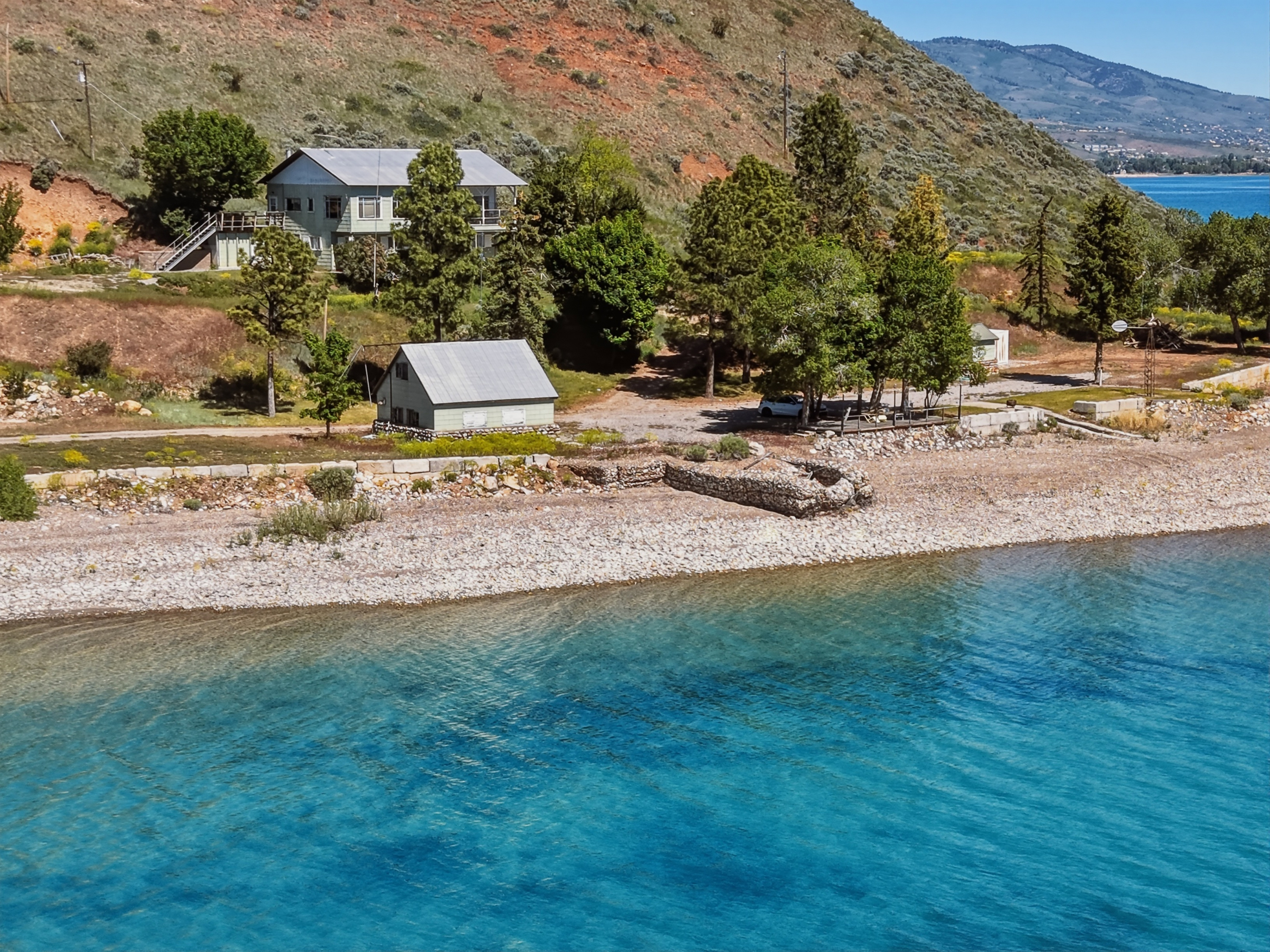 Expansive waterfront property featuring a gravel beach shoreline and clear blue waters