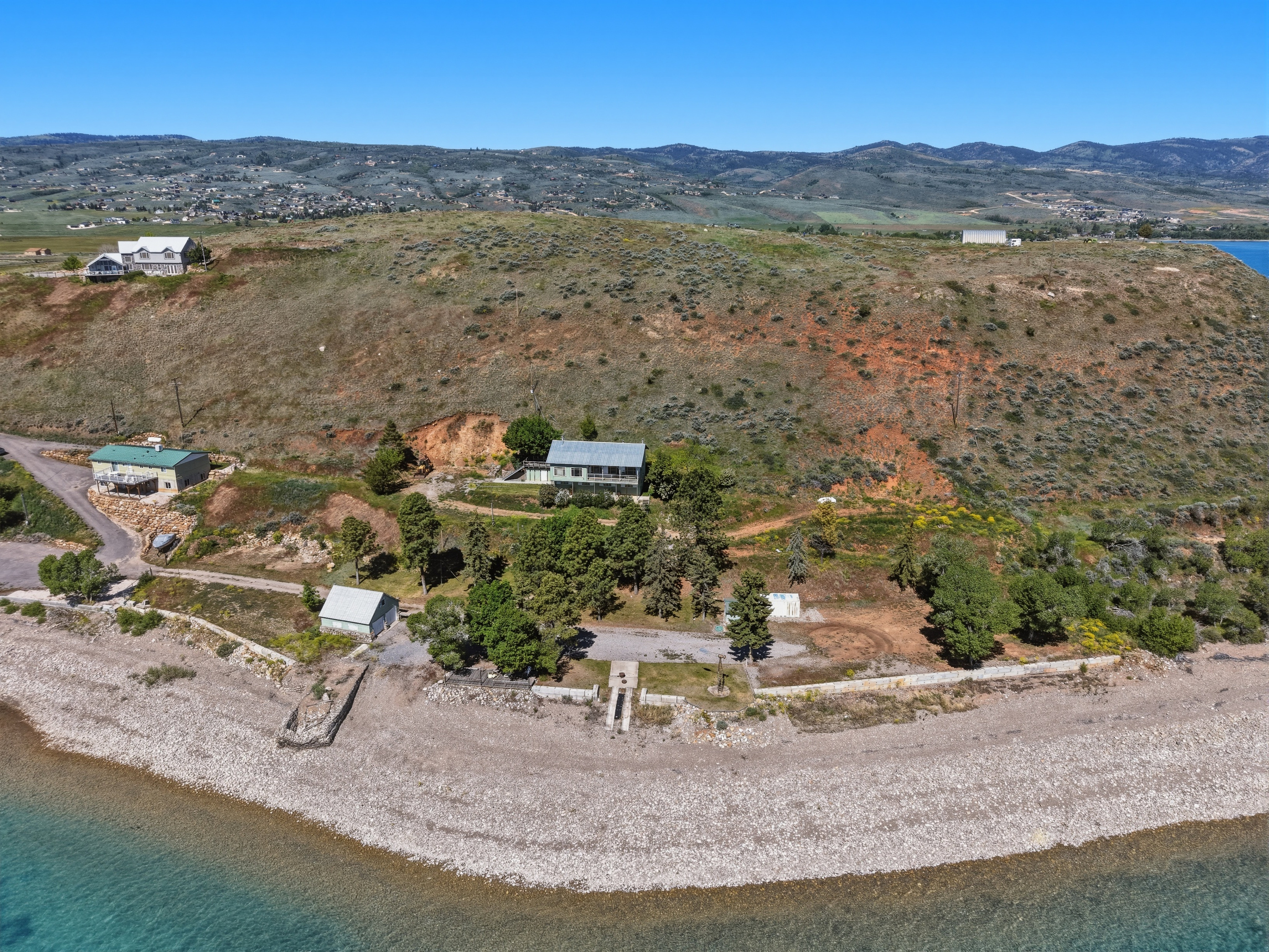 Expansive waterfront property featuring a private pebble beach, multiple residential structures, mature trees, and direct water access