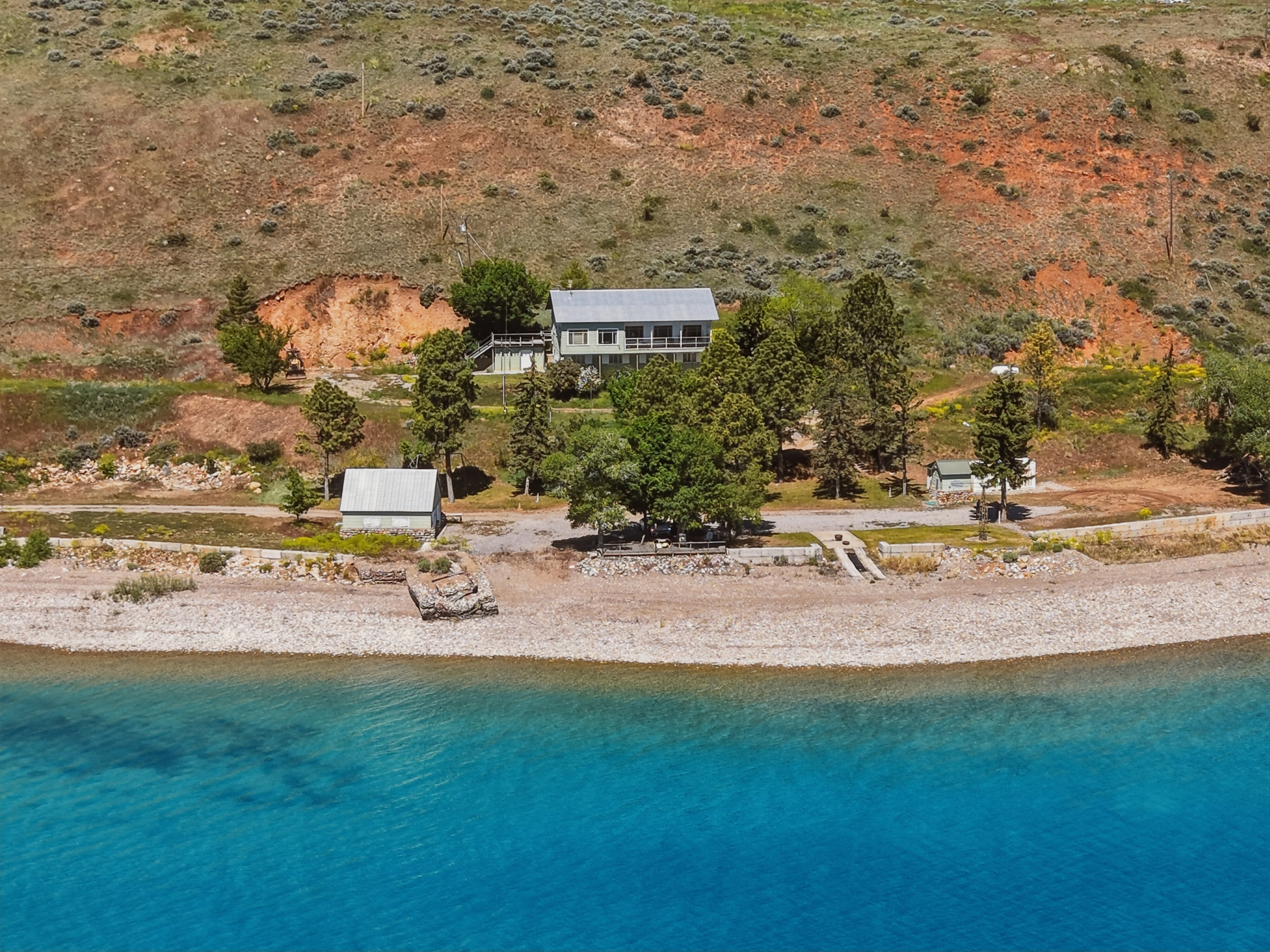 Waterfront property featuring a two-story residence, a detached auxiliary building, and a private shoreline