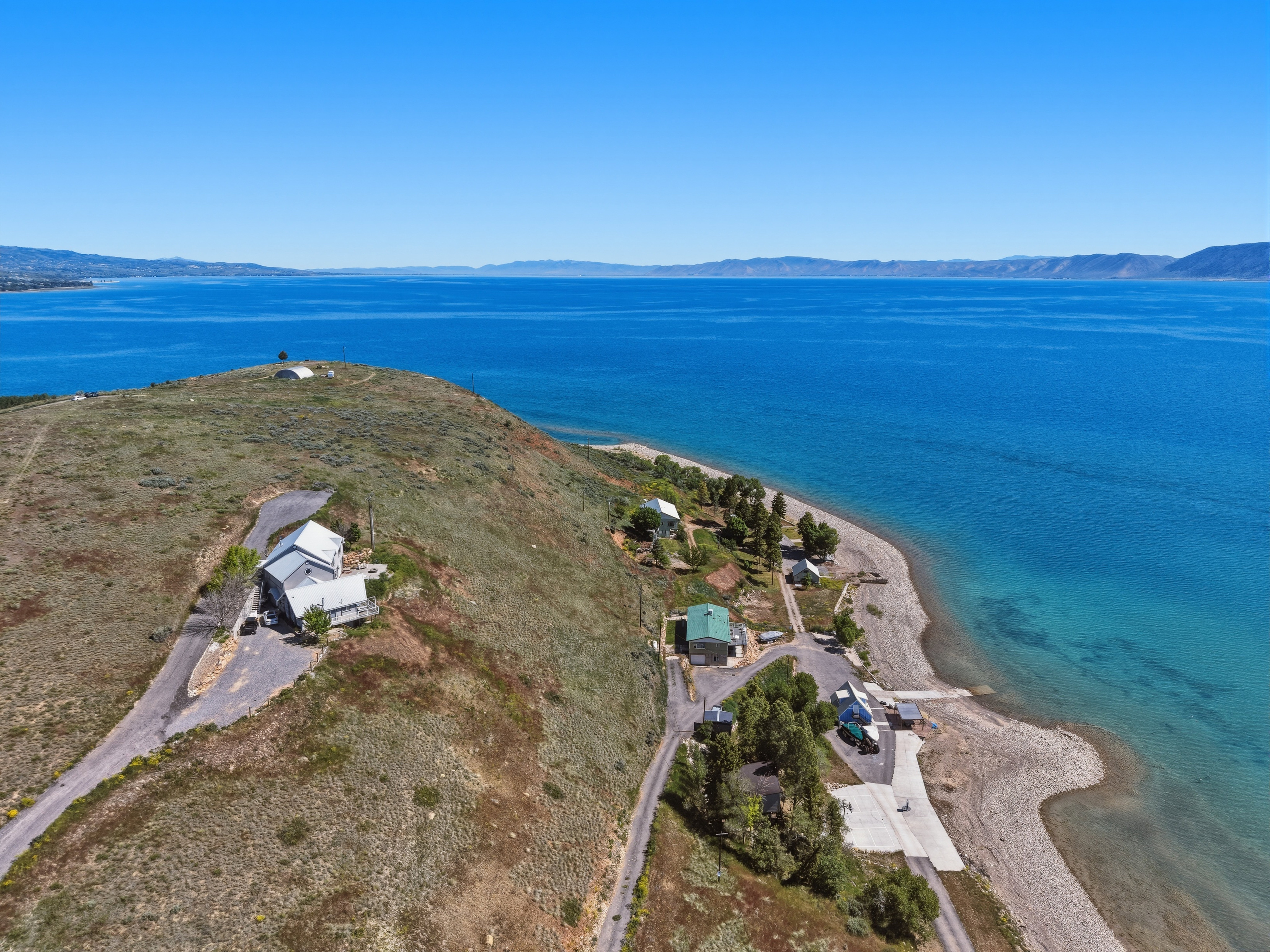 Lakeside property featuring a pitched roofline, paved drive, and stone shoreline