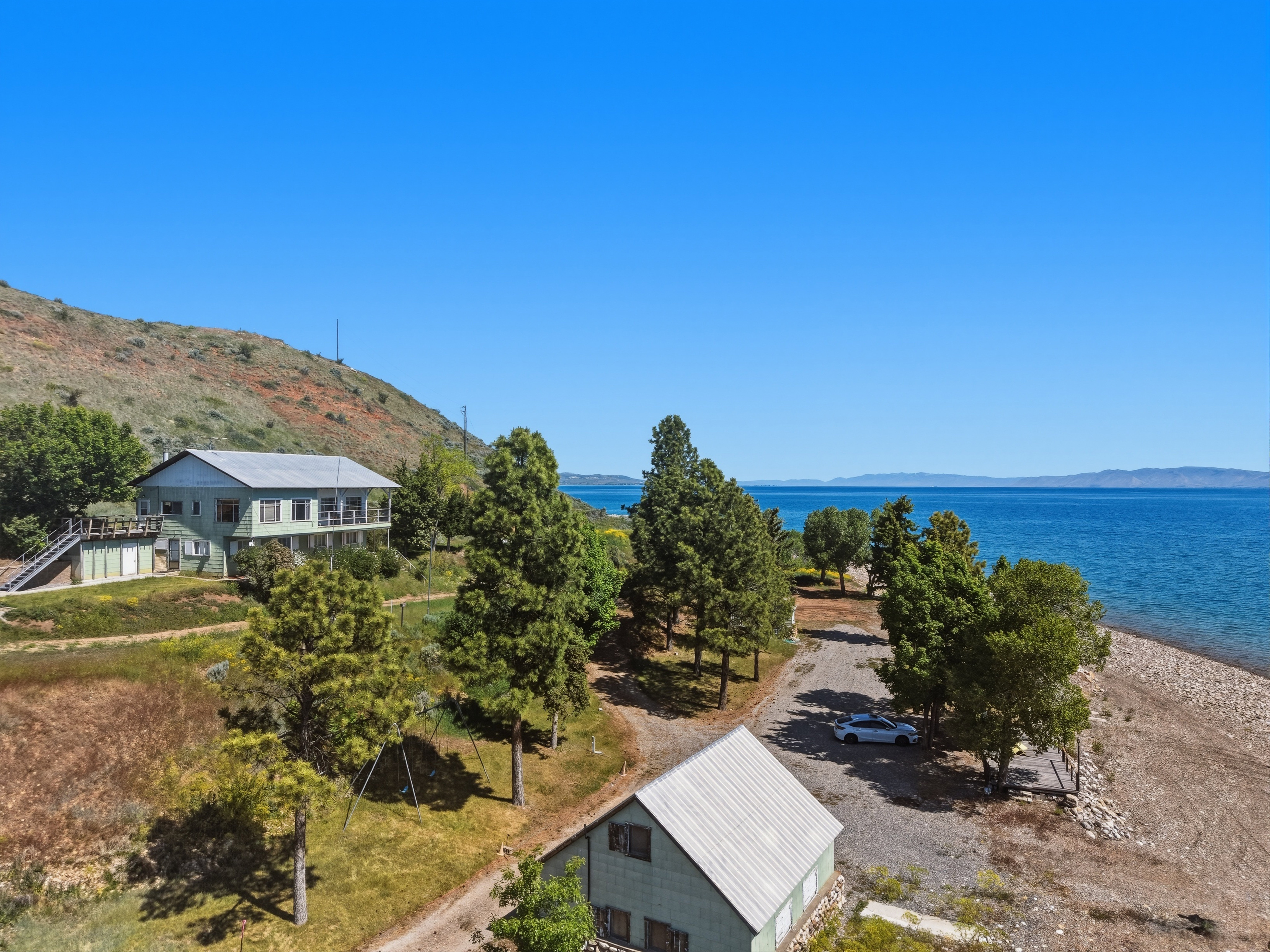 Lakeside property featuring a multi-story residence with a balcony and an additional structure