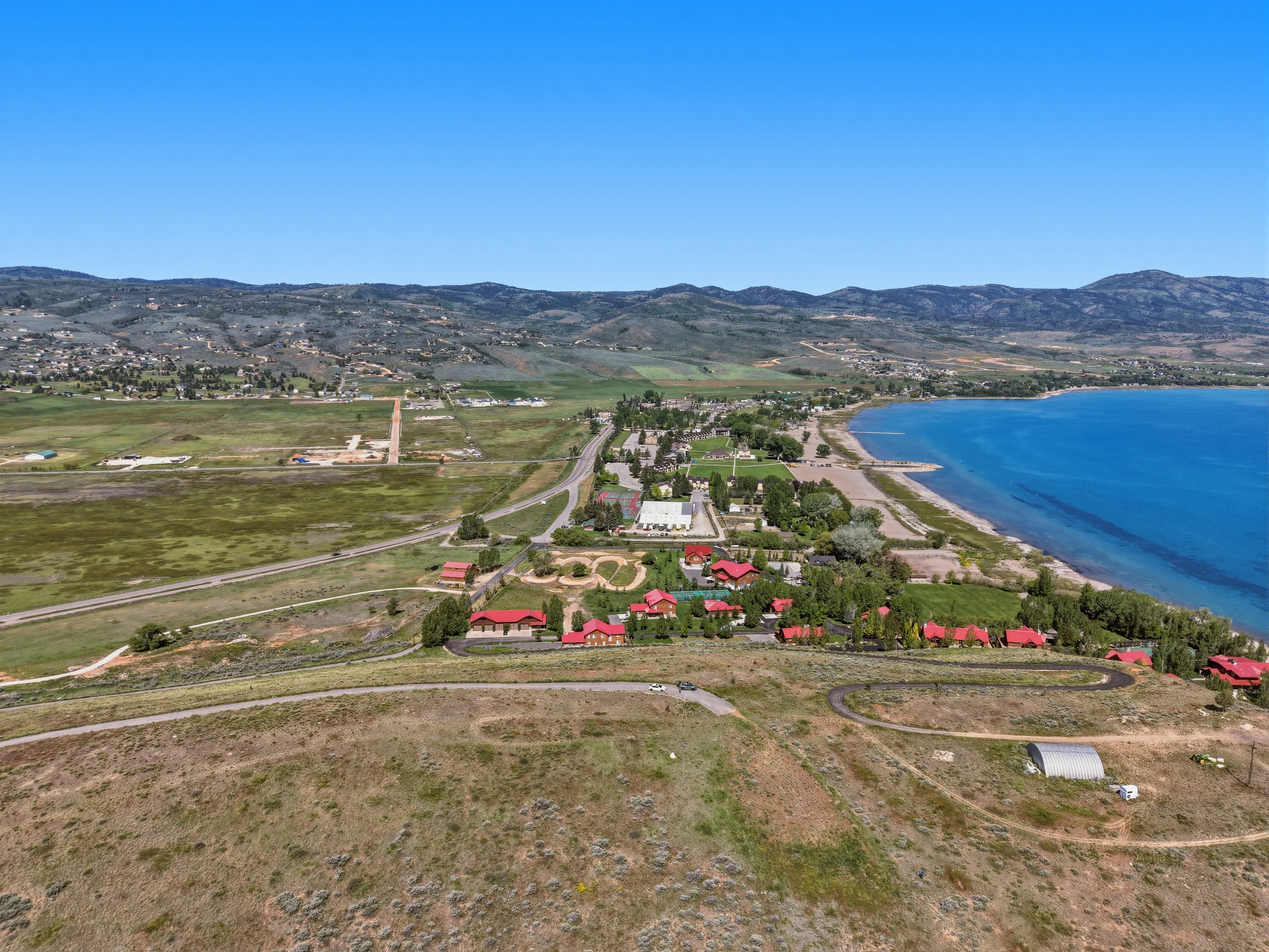 Expansive waterfront property featuring clear blue water, a sandy shoreline, and distant mountain ranges
