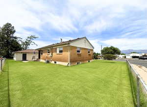 Expansive grassy lawn surrounds a brick exterior residence with a detached auxiliary building