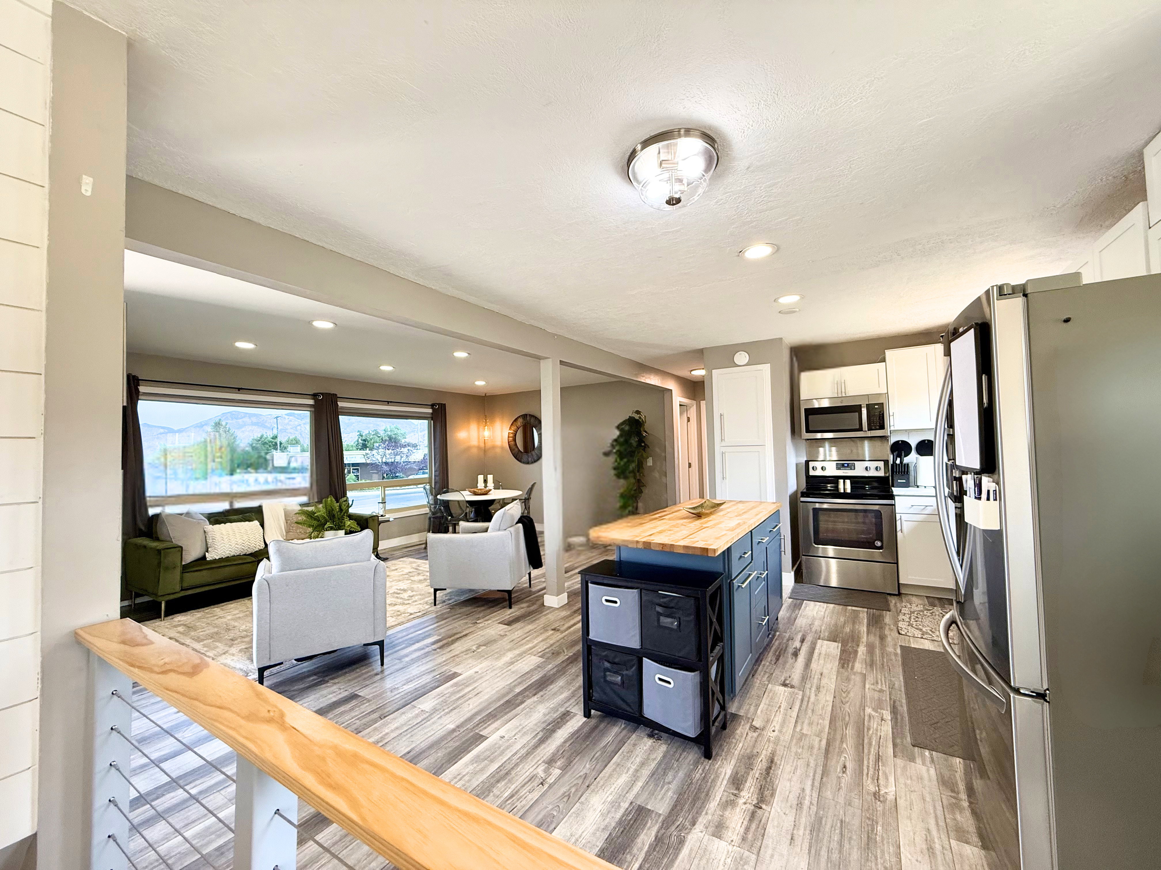 Open-concept living space featuring wood-finish flooring, recessed lighting, and large picture windows