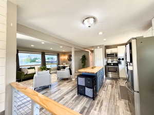 Open-concept living space featuring wood-finish flooring, recessed lighting, and large picture windows