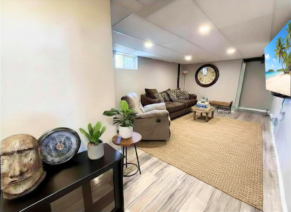 Finished living area featuring recessed lighting, wood-finish flooring, a neutral wall color, a window, and a wall-mounted display