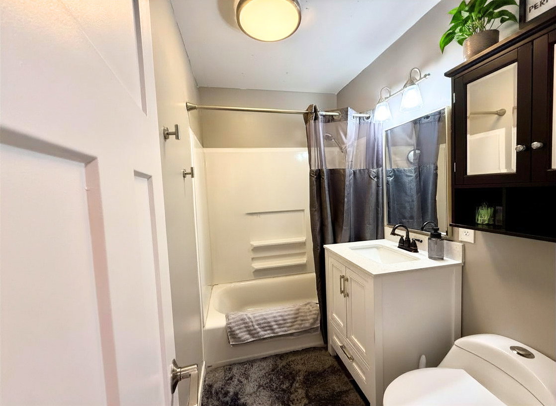 Bathroom featuring a white vanity with a rectangular sink, black faucet, and overhead three-bulb light fixture