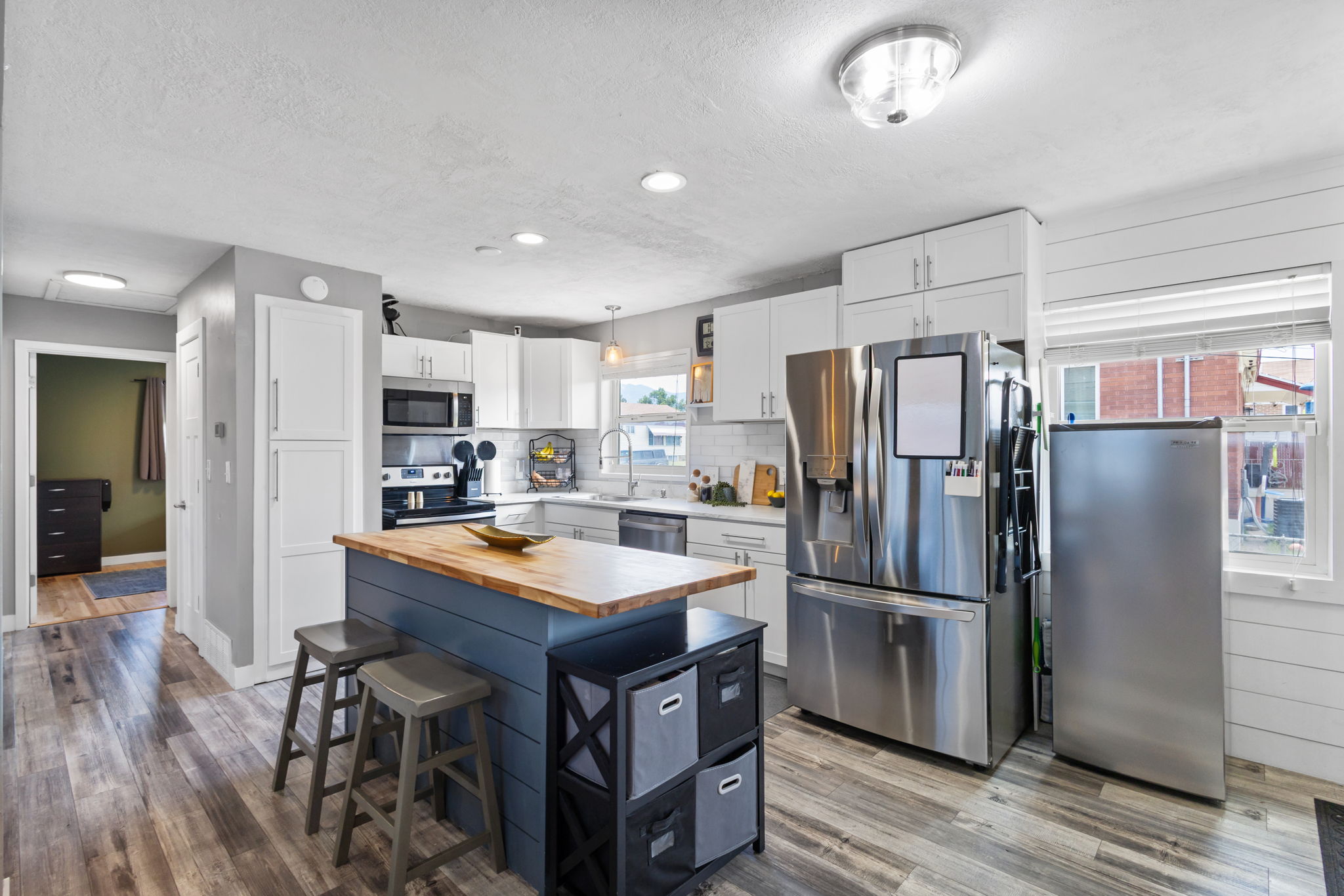 Kitchen featuring a central island with a wood-finish countertop, white cabinetry, stainless steel appliances, wood-finish flooring, and recessed lighting