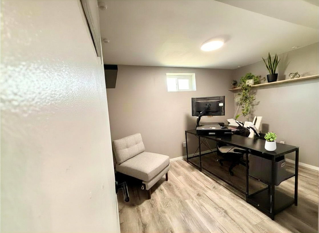 Finished room featuring wood-finish flooring, a small egress window, and recessed lighting