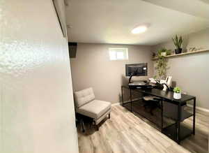 Finished room featuring wood-finish flooring, a small egress window, and recessed lighting