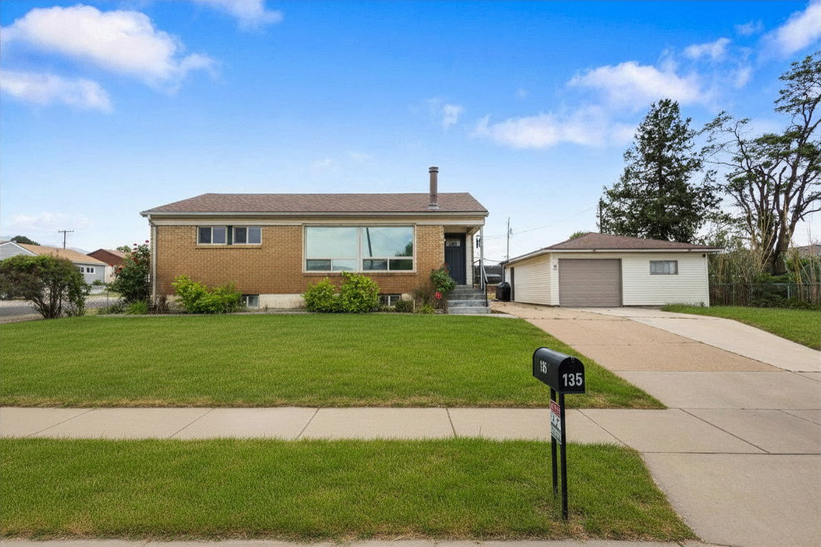 Brick facade home featuring a large front picture window, a detached garage, and a concrete driveway