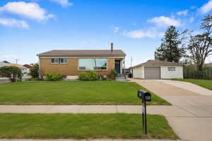 Brick facade home featuring a large front picture window, a detached garage, and a concrete driveway