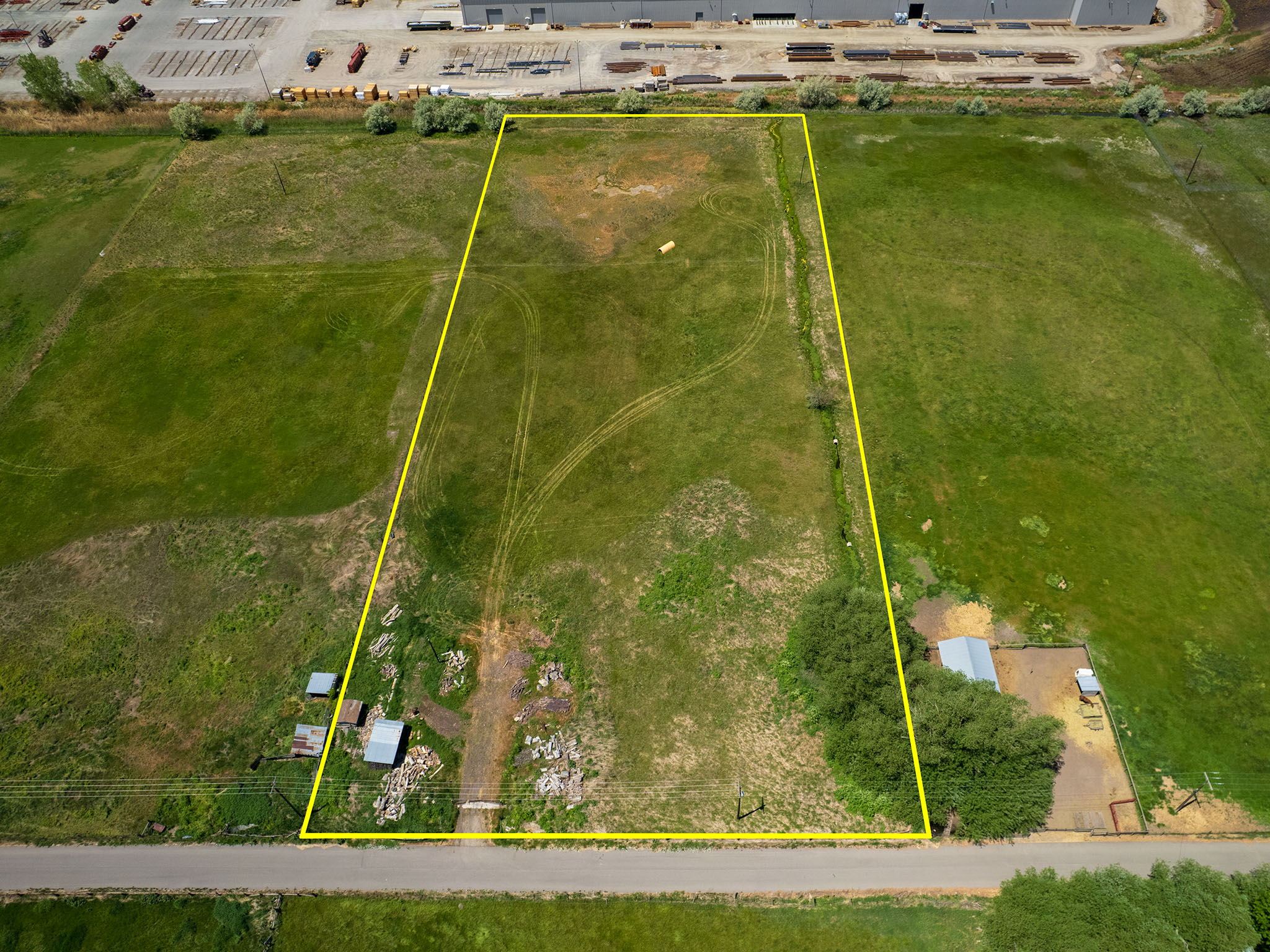 Expansive land parcel featuring existing outbuildings and mature trees