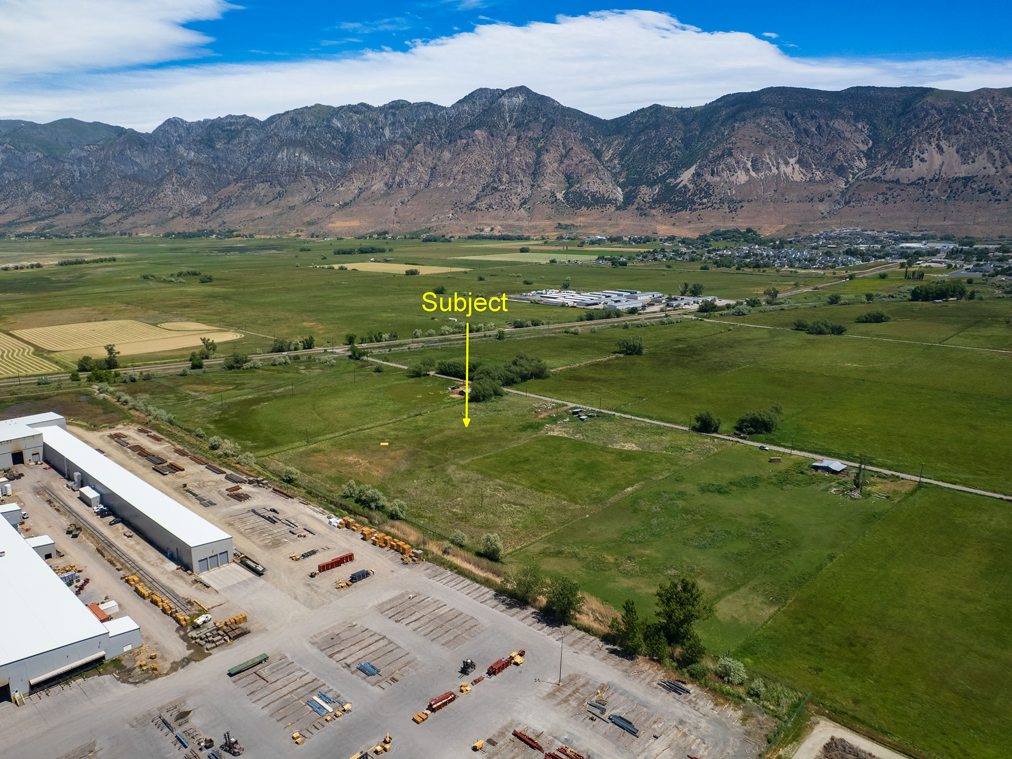 Expansive undeveloped land featuring a mountainous backdrop and proximity to industrial facilities