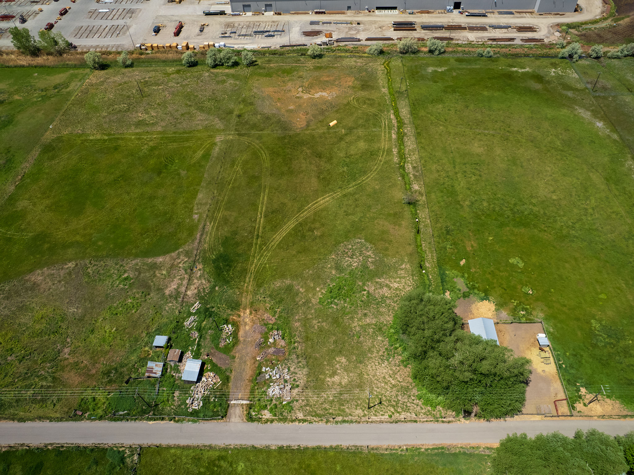 Expansive parcel featuring open green fields and a paved road frontage
