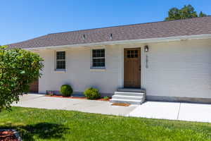 White brick exterior with a wood-finish front door, accented by a contemporary exterior light fixture and house numbers