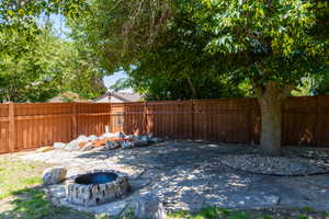 Backyard featuring a stone fire pit, extensive flagstone patio, and mature shade trees