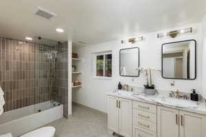 Dual vanity with white cabinetry, gold-toned hardware, and a marble-patterned countertop