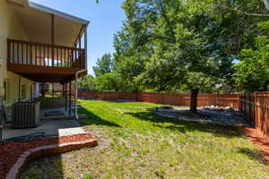Expansive backyard featuring a manicured lawn, a large shade tree, and a full privacy fence