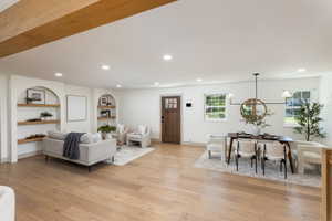 Expansive open-concept living space featuring light wood-finish flooring, recessed lighting, and exposed ceiling beams
