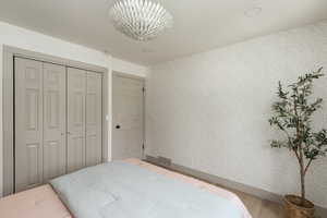 Bedroom featuring light wood-finish flooring, a contemporary ceiling light fixture, bi-fold closet doors, and textured wall finish