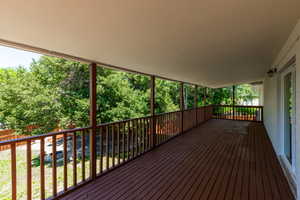 Expansive covered deck featuring wood-finish flooring, wood railings, and a solid ceiling