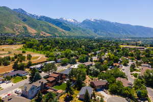 Expansive mountain range backdrop framing a residential neighborhood with mature trees, green spaces, and curving streets