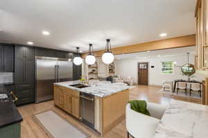 Gourmet kitchen featuring a large central island with a waterfall countertop, integrated sink, and dishwasher