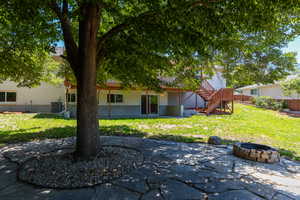 Expansive backyard featuring a natural stone patio, mature shade tree, and fire pit