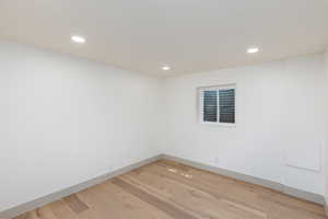 Room featuring wood-finish flooring, recessed lighting, and a white window with horizontal blinds