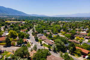 Expansive residential area featuring established homes, mature trees, paved streets, and mountainous terrain in the background