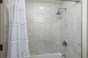 Bathtub with full-height square tile surround and chrome fixtures