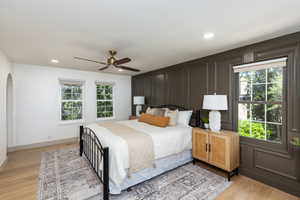 Hardwood-finish flooring complementing a paneled accent wall, recessed lighting, and a ceiling fan with integrated lighting