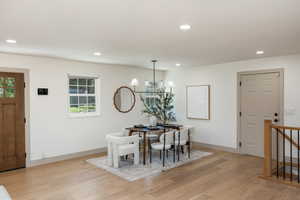 Spacious room featuring light wood-finish flooring, recessed lighting, and a modern chandelier