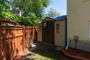 Outdoor storage shed featuring double doors with decorative windows and a peaked roof