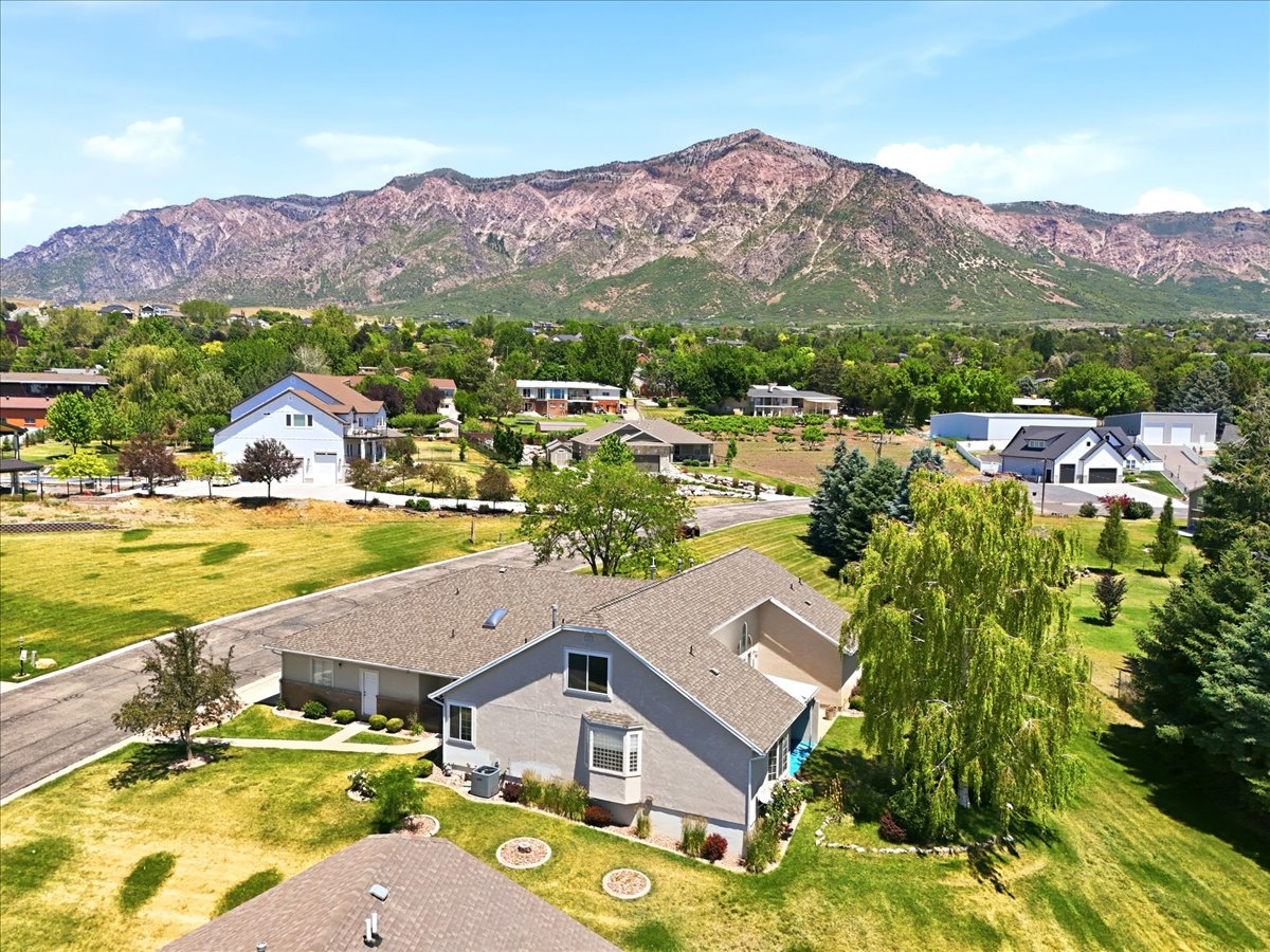 Expansive property featuring a contemporary residence with a bay window, mature trees, and a mountain backdrop