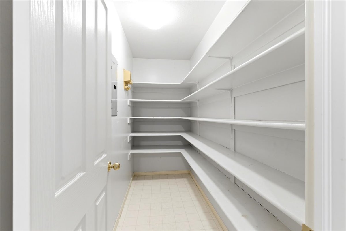 Spacious pantry featuring extensive white shelving, recessed lighting, and light-toned flooring