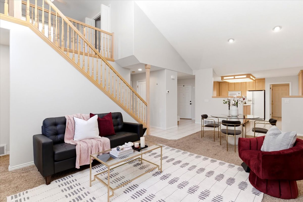 Vaulted ceiling living area with a staircase featuring wood balusters and a wood handrail